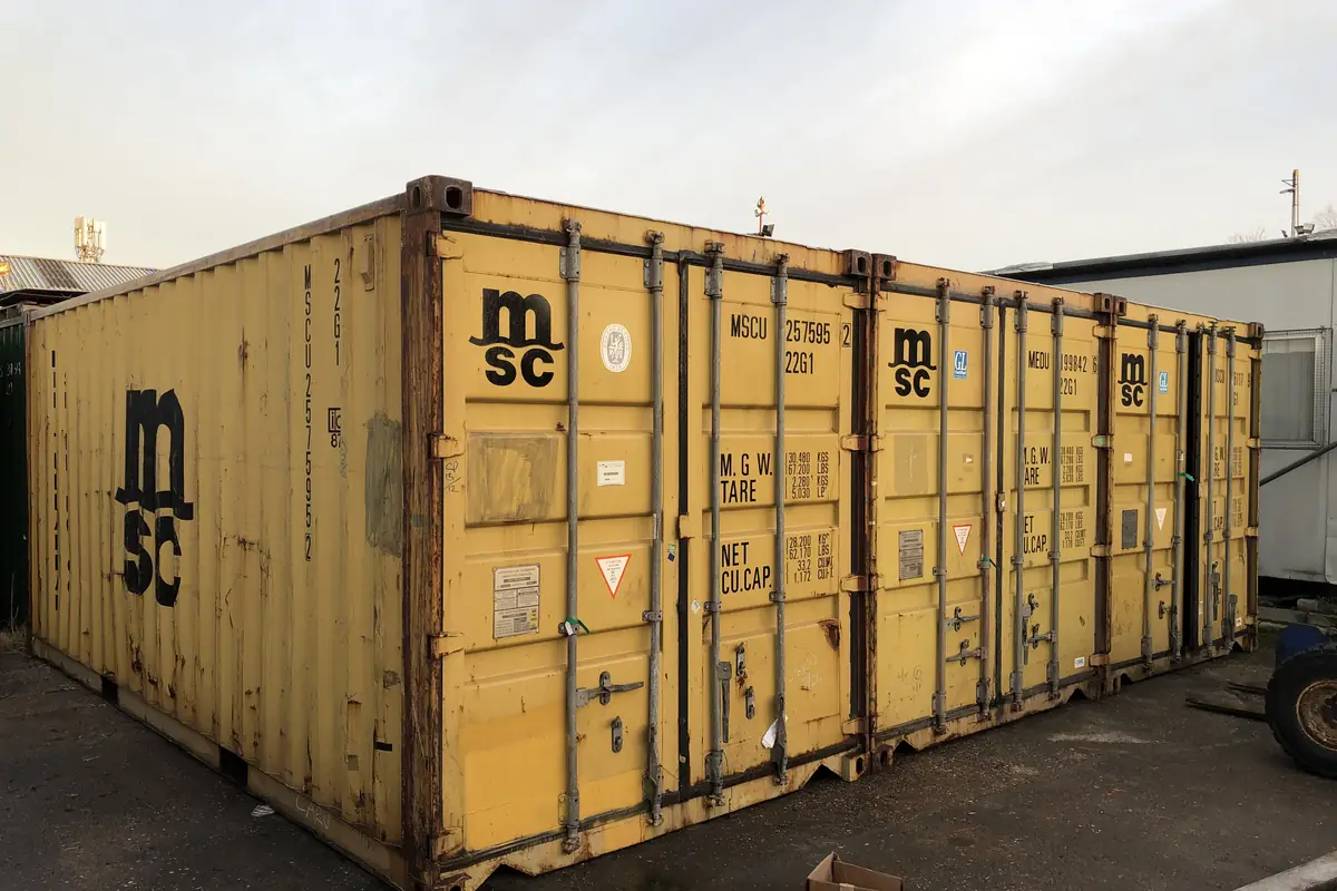 Row of used shipping containers standing side by side in a yard
