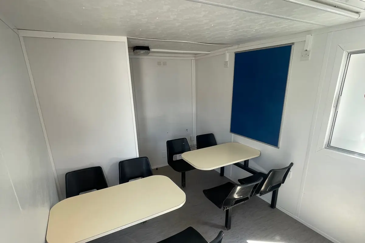 Inside a used welfare unit showing canteen tables and seating
